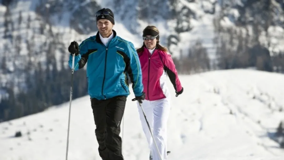 Zwei Personen beim Skilanglauf auf verschneitem Berg.