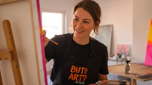 Woman painting on canvas in art studio.