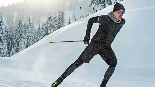 Mann fährt schnell Ski auf verschneitem Bergweg.