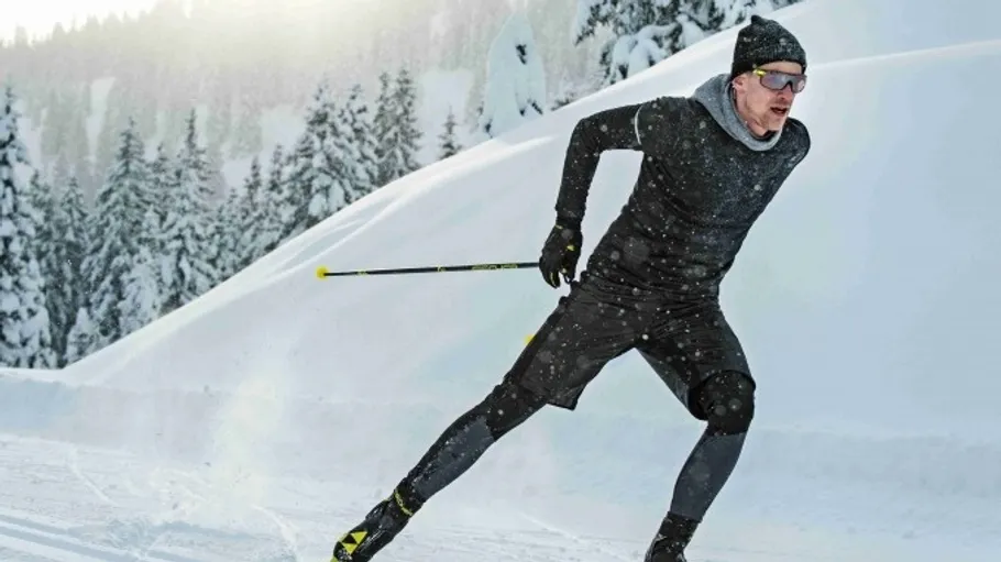 Mann fährt schnell Ski auf verschneitem Bergweg.