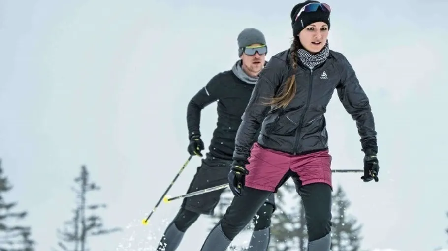 Zwei Personen beim Skilanglauf in verschneiter Landschaft.