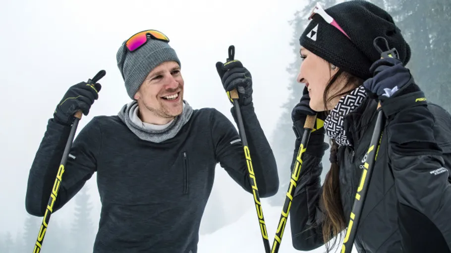 Two people smiling while holding ski poles.