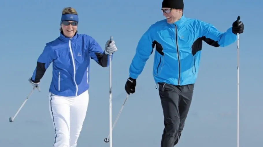 Zwei Personen beim Skifahren auf Schnee mit Stöcken.