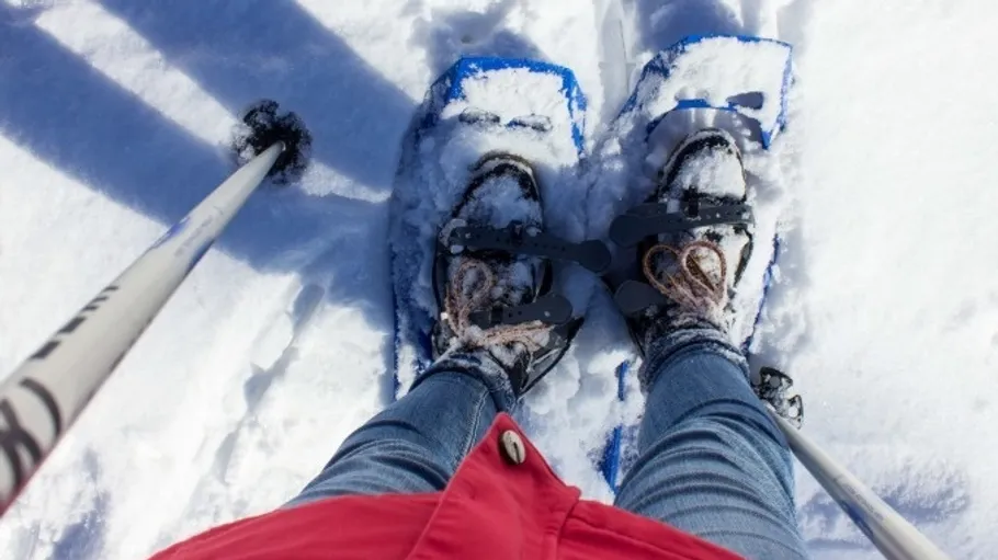 Person trägt Schneeschuhe auf verschneitem Boden.