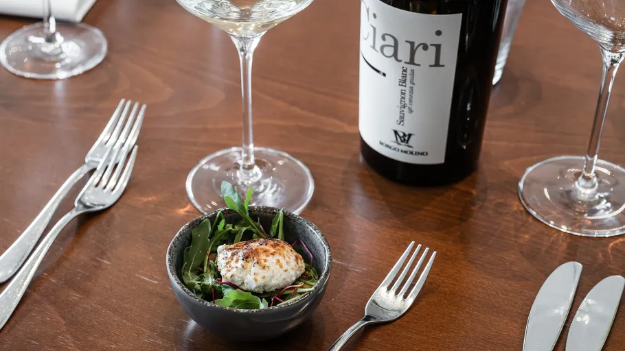 Salad with glass of wine on table.