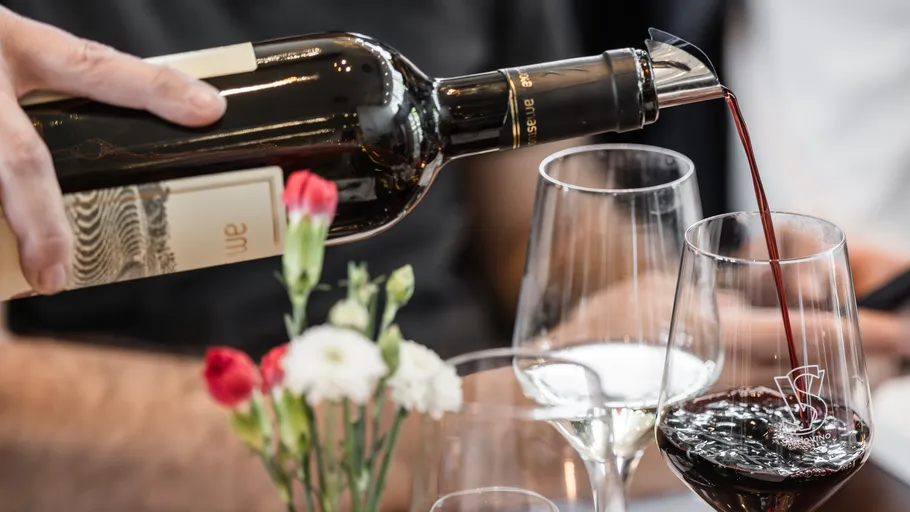 Wine being poured into glass on table.