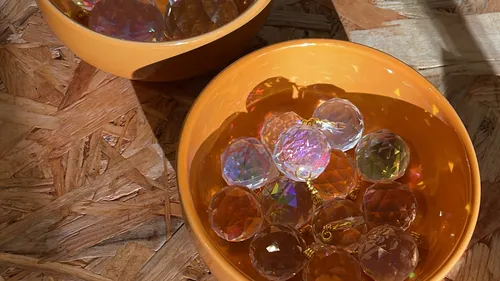 Colored crystals in orange bowls on wood surface.