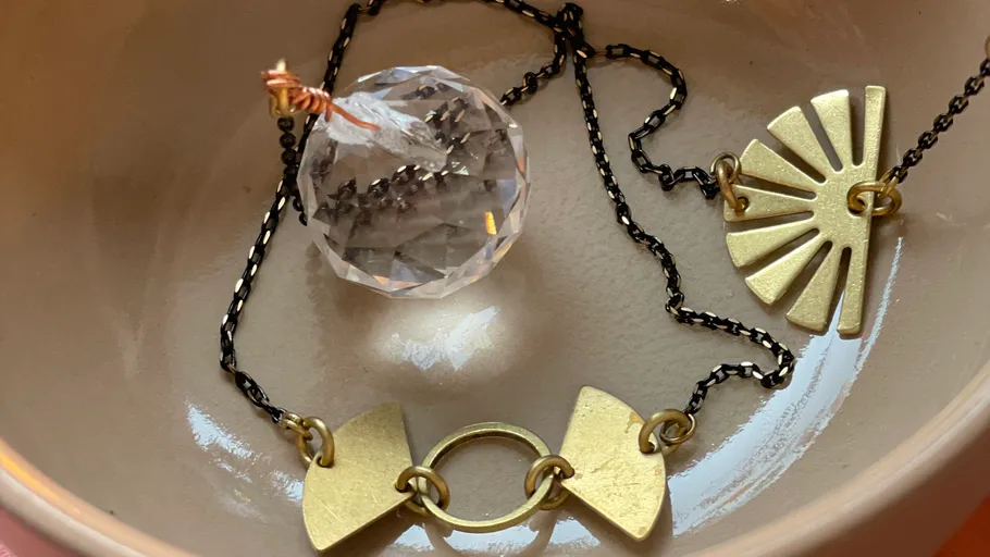 Necklace with geometric pendants in a bowl.