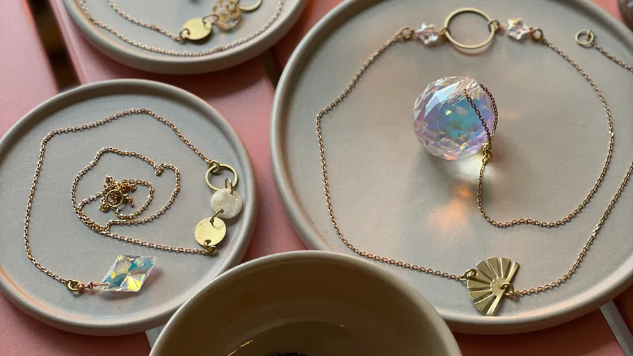 Schmuck auf Tellern mit rosa Hintergrund.