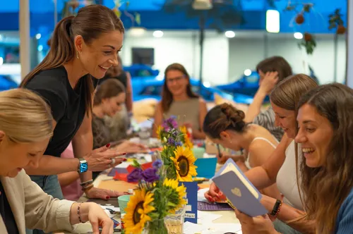 Frauen basteln an einem Tisch mit Blumen.