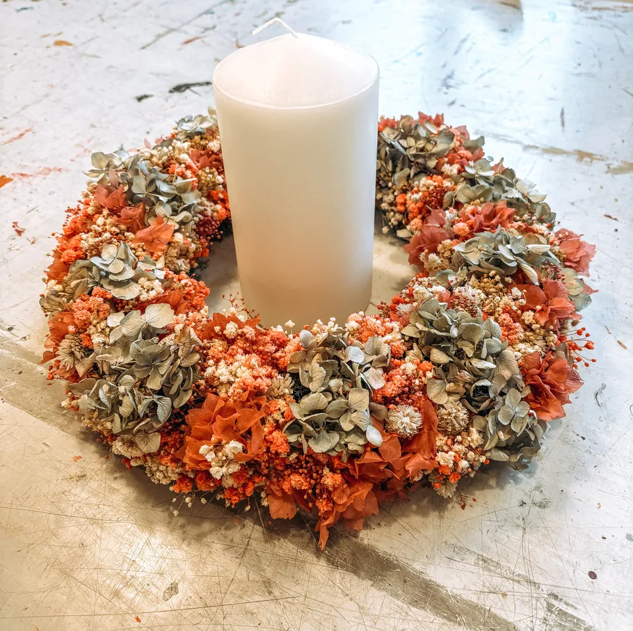 Blumenkranz mit Kerze auf Tisch.