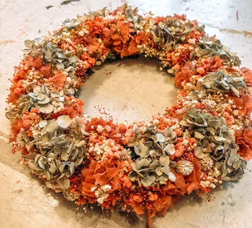 Blumenkranz mit getrockneten Blumen auf Tisch.