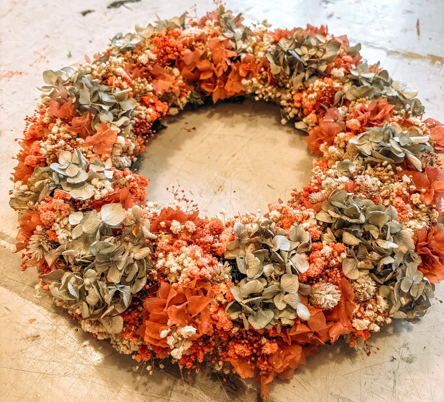 Blumenkranz mit getrockneten Blumen auf Tisch.