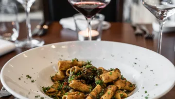 Pasta in white bowl with red wine.
