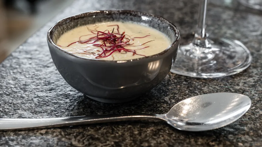 Suppenschale mit Garnierung, Löffel in der Nähe.