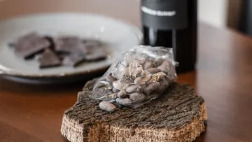 Cocoa beans in bag on wooden surface.