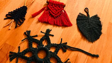 Four macramé ornaments on a wooden surface.