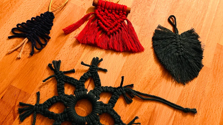 Four macramé ornaments on a wooden surface.