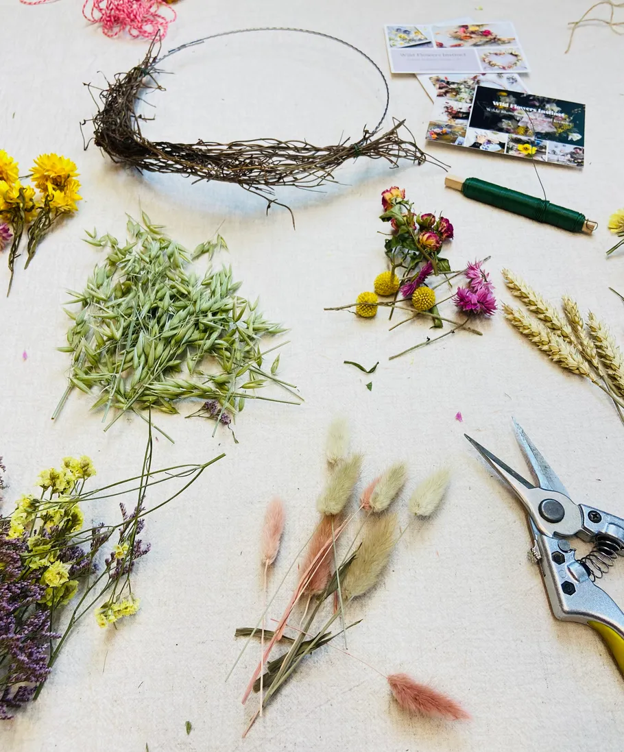 Materialien und Werkzeuge für Blumenkranz auf Tisch.