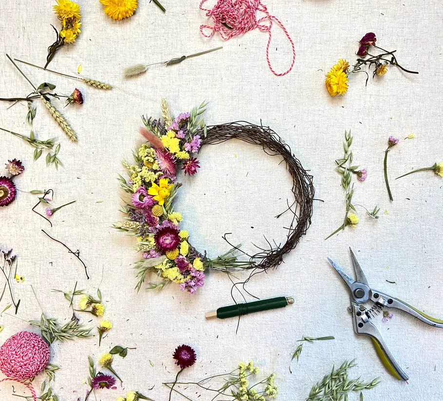Floral wreath making on a beige surface.