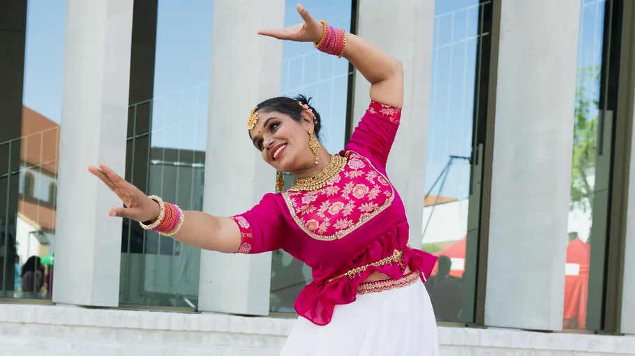 Dancer in traditional attire performing outside building.