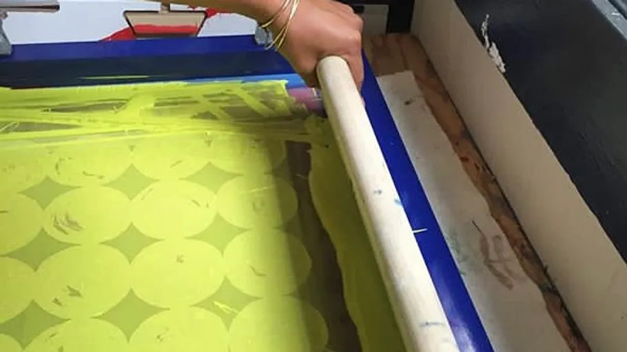 Hand using squeegee in screen printing.