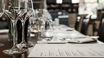 Wine glasses and menu on table in restaurant.