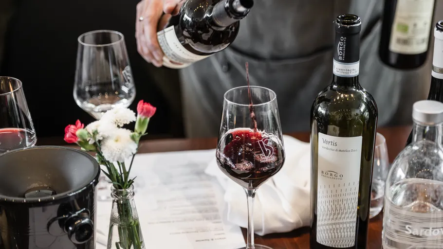 Person pouring red wine into a glass.