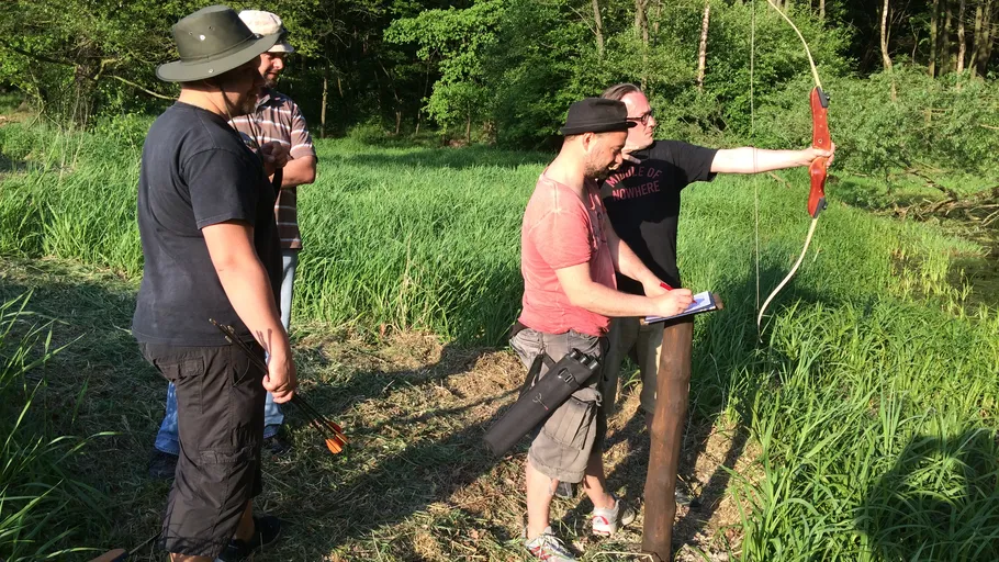 Group archery practice in grassy field.