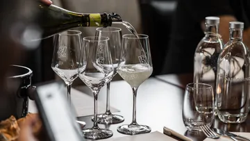 Champagne being poured into glasses at table.