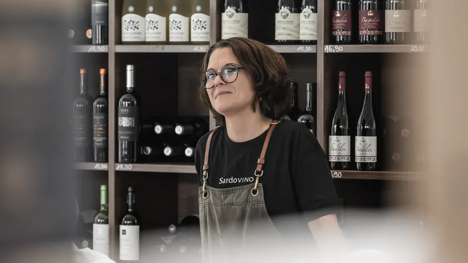 Person standing in front of wine shelves.