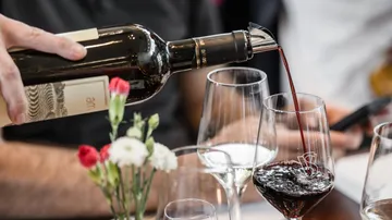 Rotwein wird in ein Glas eingeschenkt.