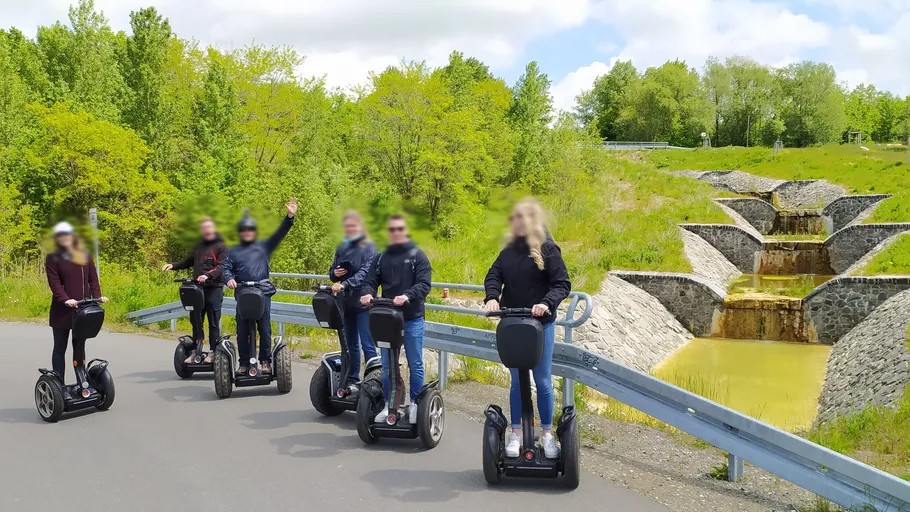 Personen fahren Segways auf einem malerischen Weg.