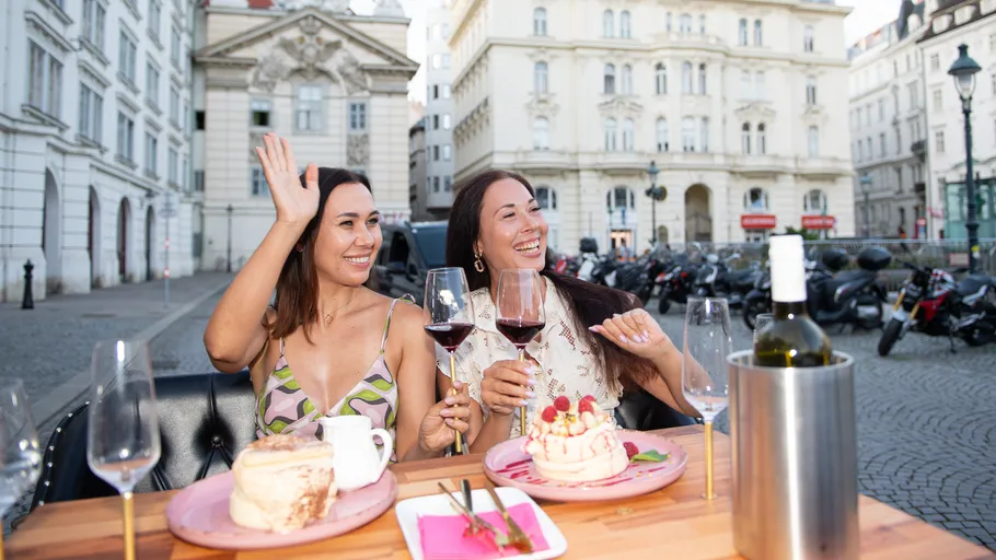 Zwei Frauen genießen Wein am Außentisch.
