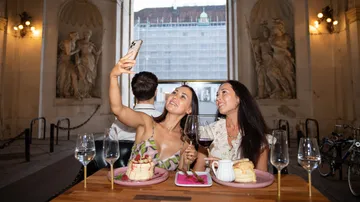 Two women taking selfie at a cafe.