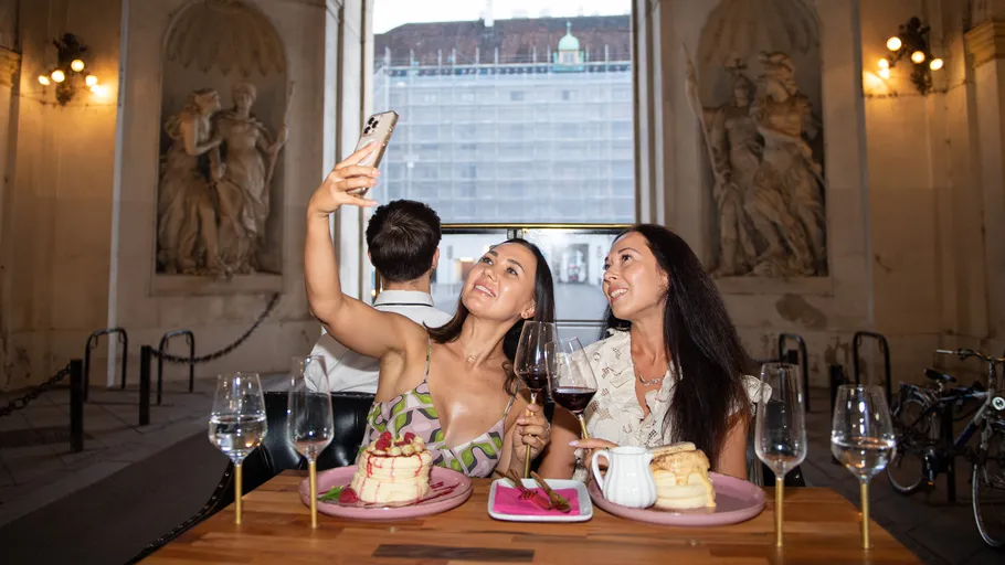 Two women taking selfie at a cafe.