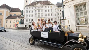 Group in vintage car, city center.