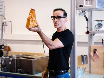 Man holds big yellow stone in a modern laboratory.