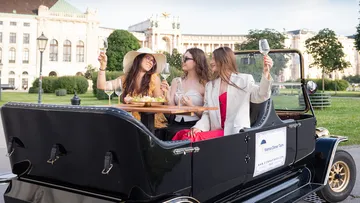 Drei Frauen genießen Getränke in einem Tourenfahrzeug.