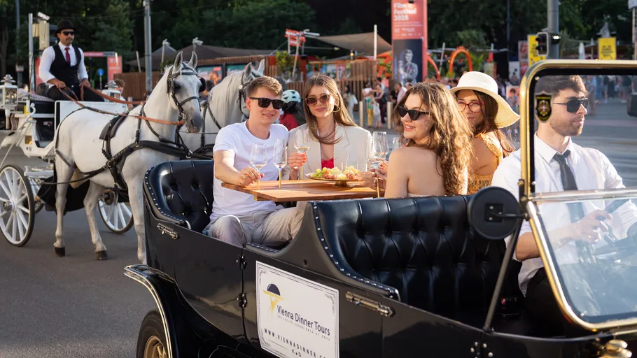 Personen speisen im Oldtimer mit naher Kutsche.