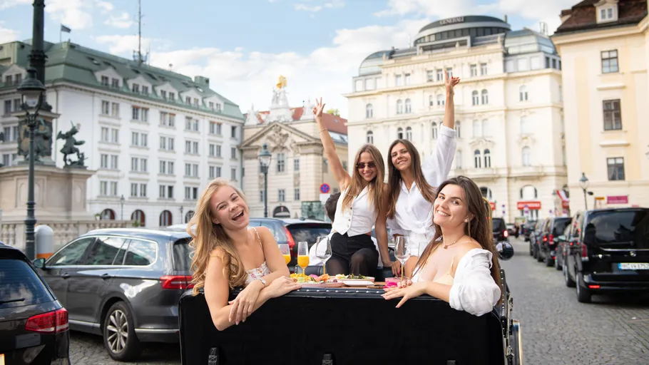 Vier Frauen speisen an Tisch auf Stadtstraße.