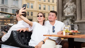 Leute machen Selfie, sitzen im Außenbereich eines Cafés.