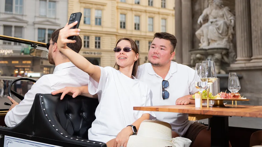 People taking selfie, sitting at outdoor cafe.