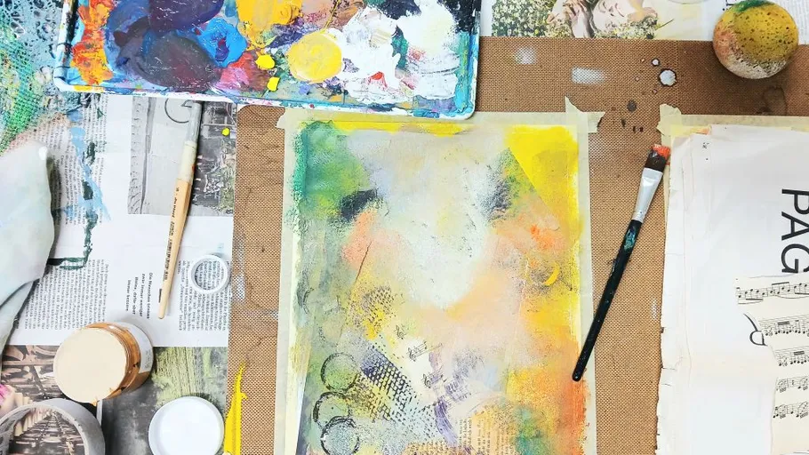 Kunstmaterialien und bemalte Leinwand auf Tisch.