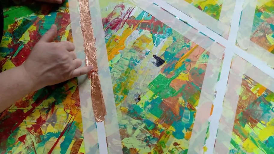 Person applying copper foil on colorful painting