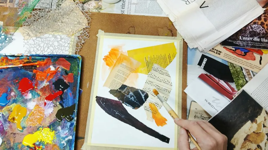 Hands creating collage with paint and paper.