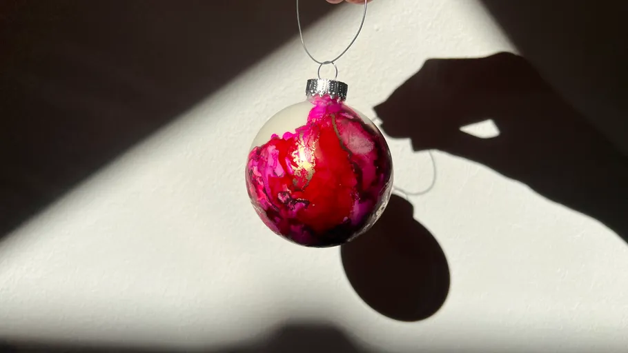 Hand hält dekorierte Weihnachtskugel mit Schatten.