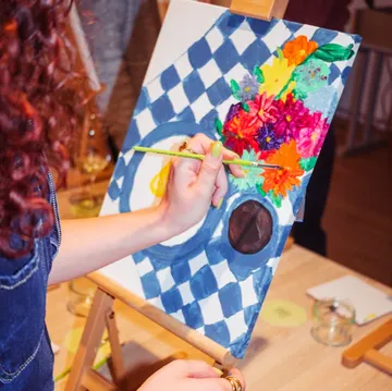 Person painting colorful flowers on canvas.