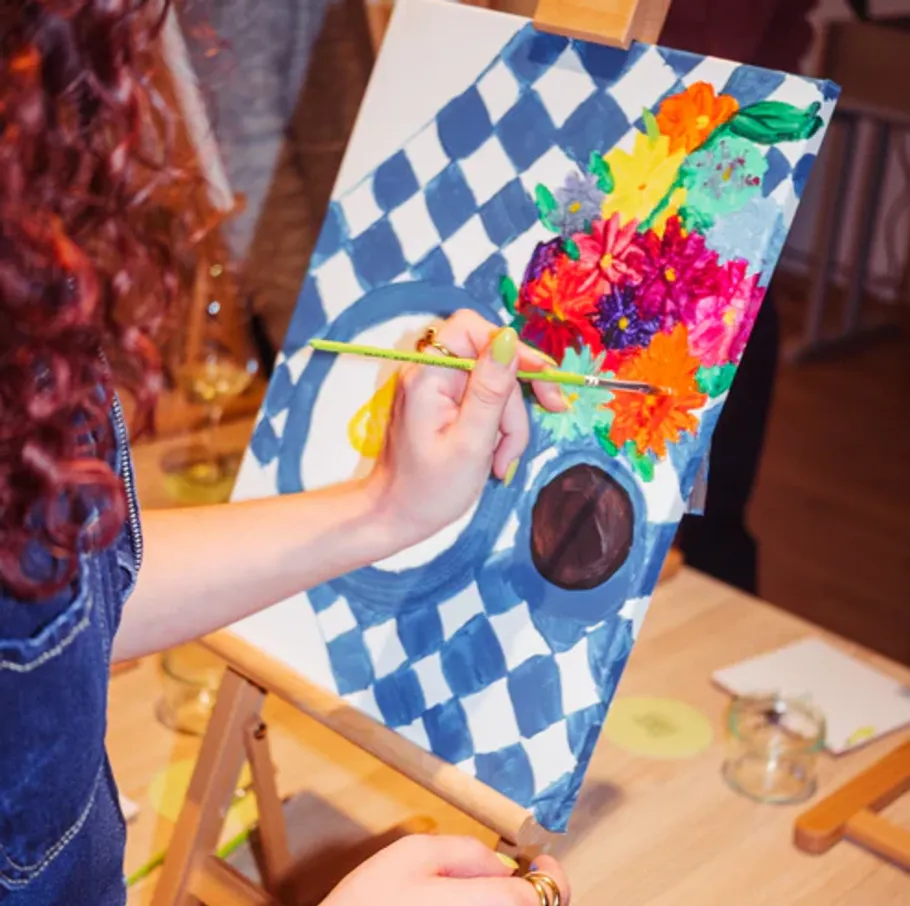 Person painting colorful flowers on canvas.