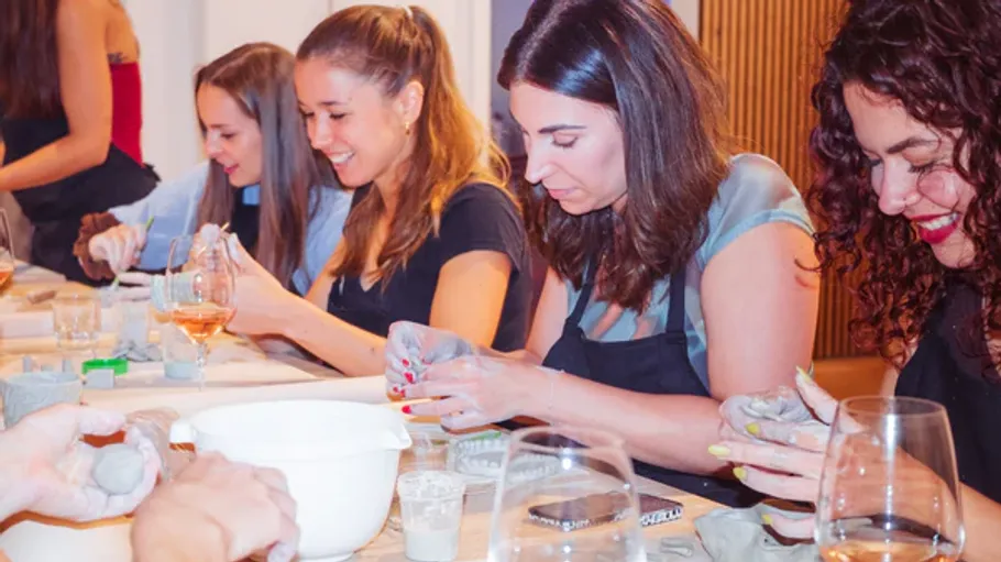 Women sculpting clay at a table indoors.